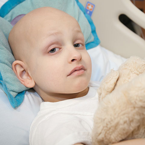 Child with stuffed animal in hospital bed